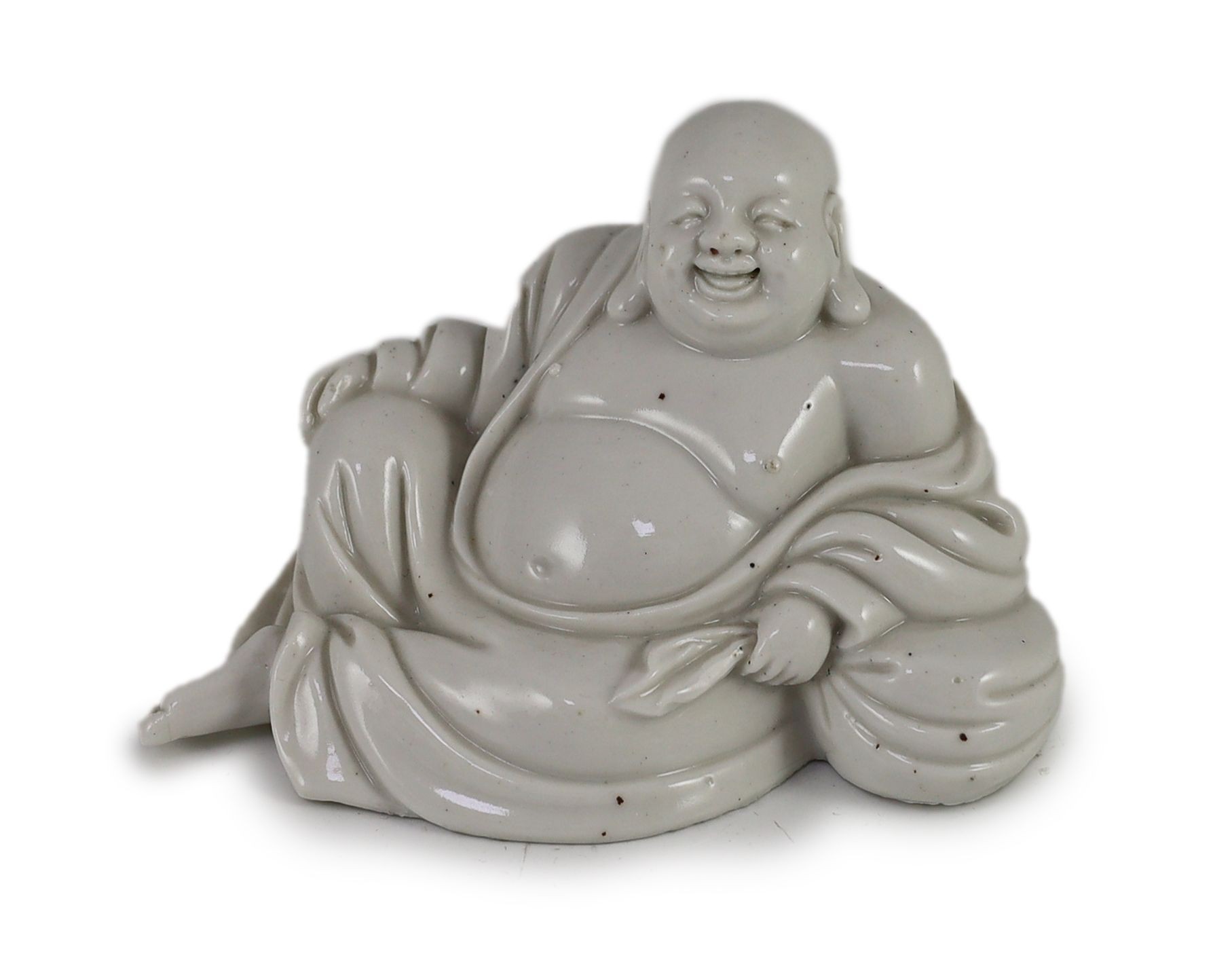 CORRECTION CIRCA 1900 A Chinese blanc-de-chine reclining figure of a smiling Budai, Dehua kilns, 15cm wide